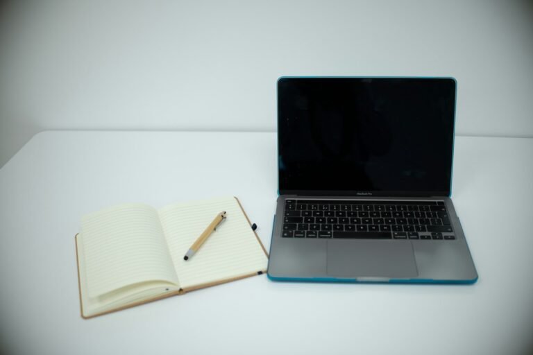 Laptop and open notebook on a writing desk