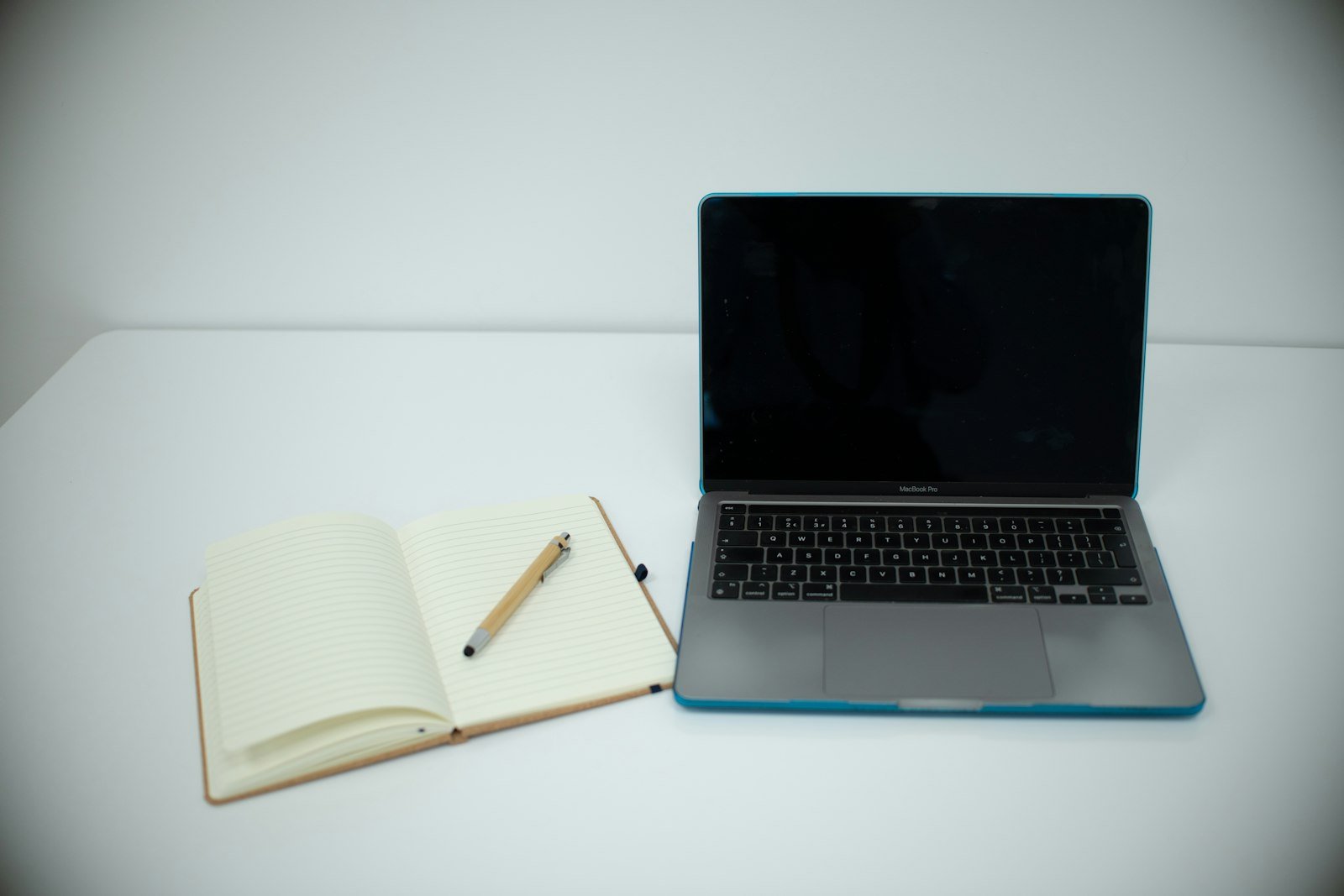 Laptop and open notebook on a writing desk
